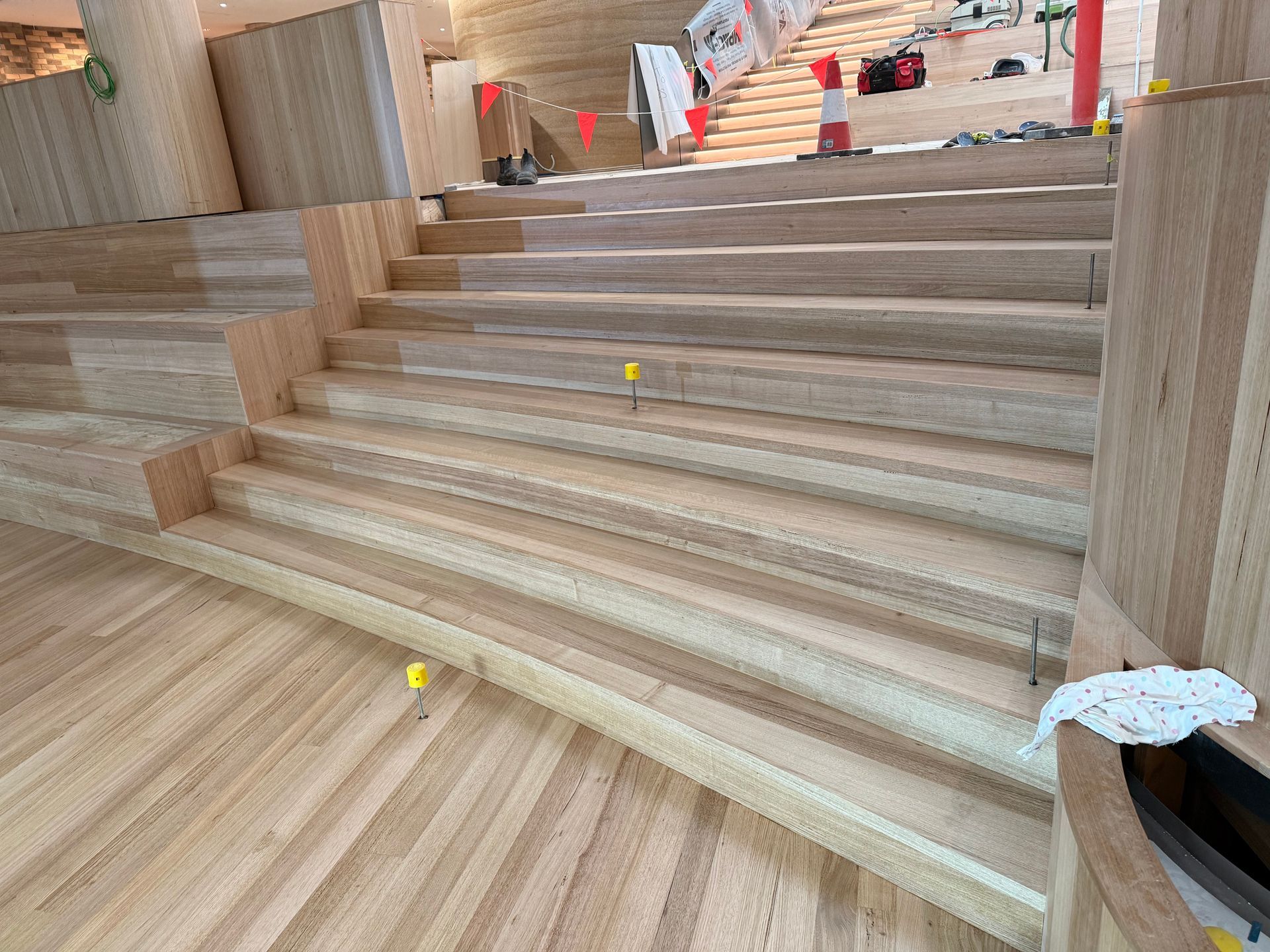 Wide wooden staircase under construction with unfinished steps and scattered tools in a building interior — Finer Floors In Cambridge, TAS