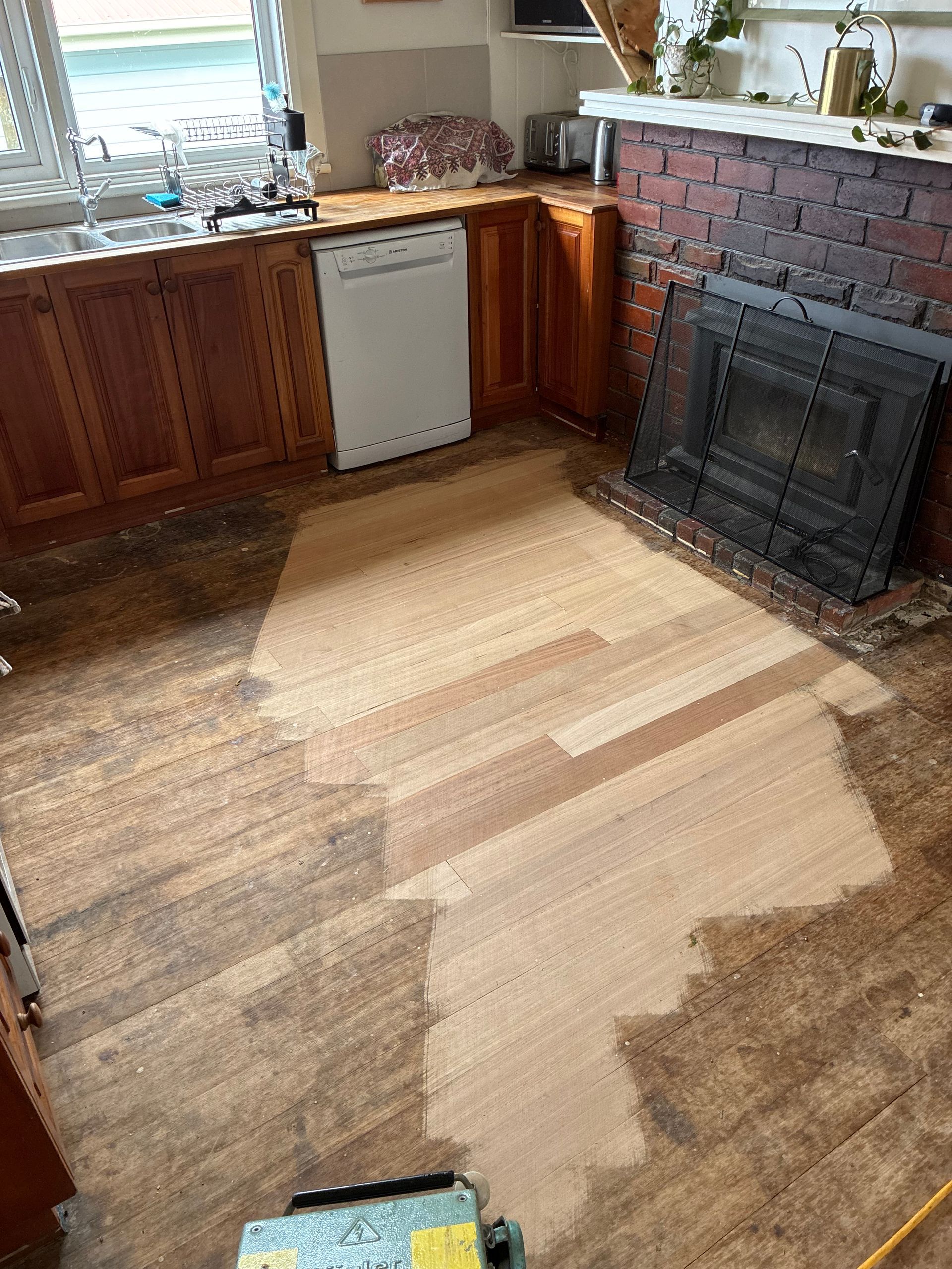 Living room with damaged carpet, wooden cabinets, and a brick fireplace mantle — Finer Floors In Cambridge, TAS