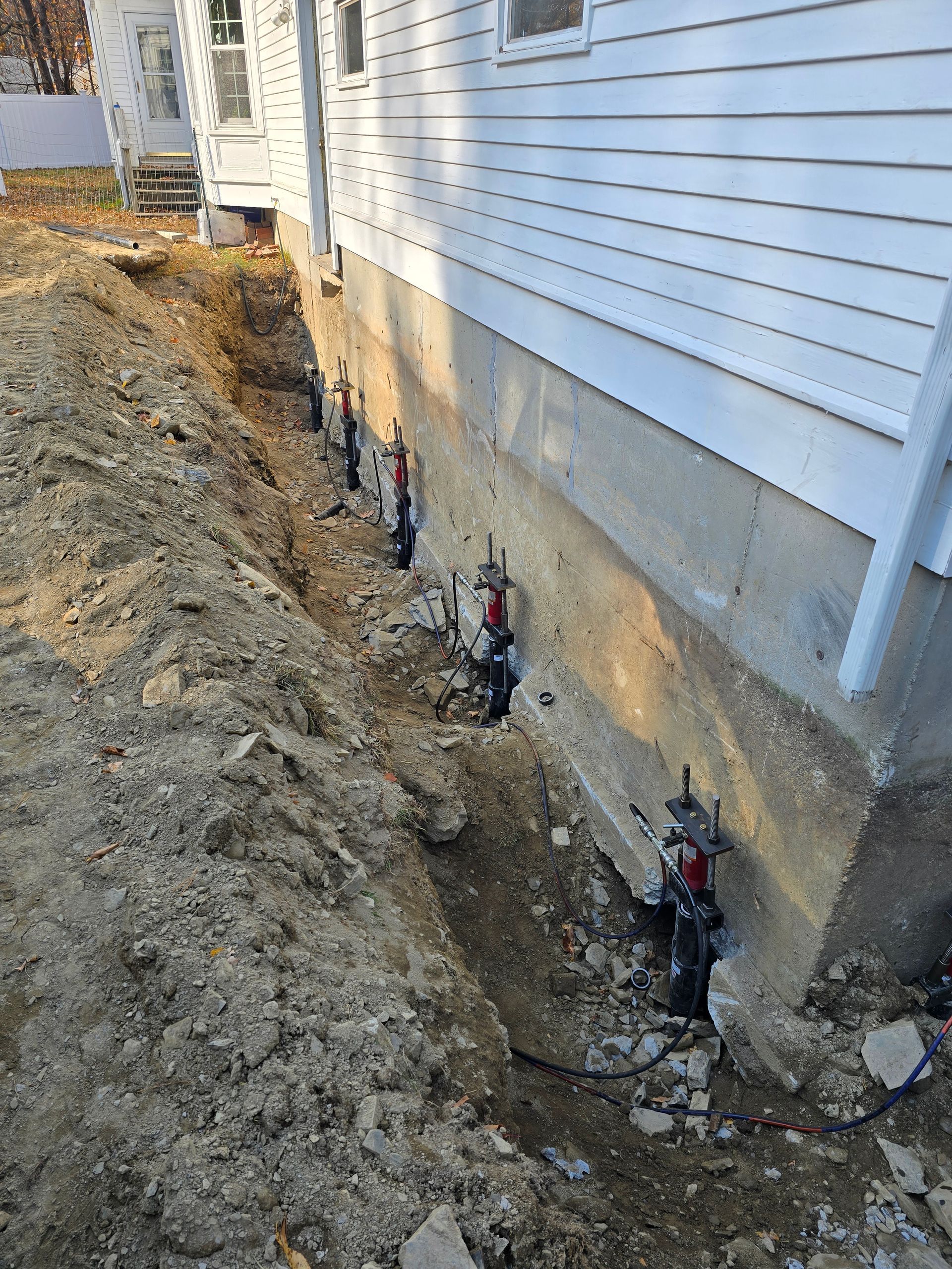 A close-up view of a grey speckled epoxy porch floor with a dark decorative urn and a house wall in the background.