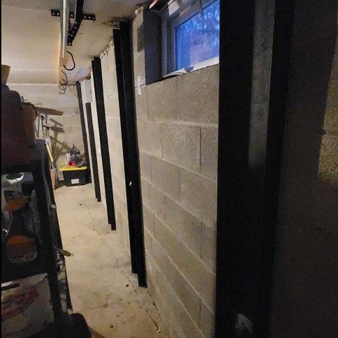 Basement interior with concrete block walls, dark support beams, and a small window.