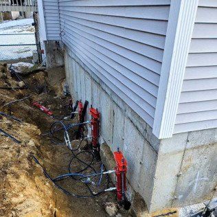 Foundation repair, with jacks, excavation, and house.