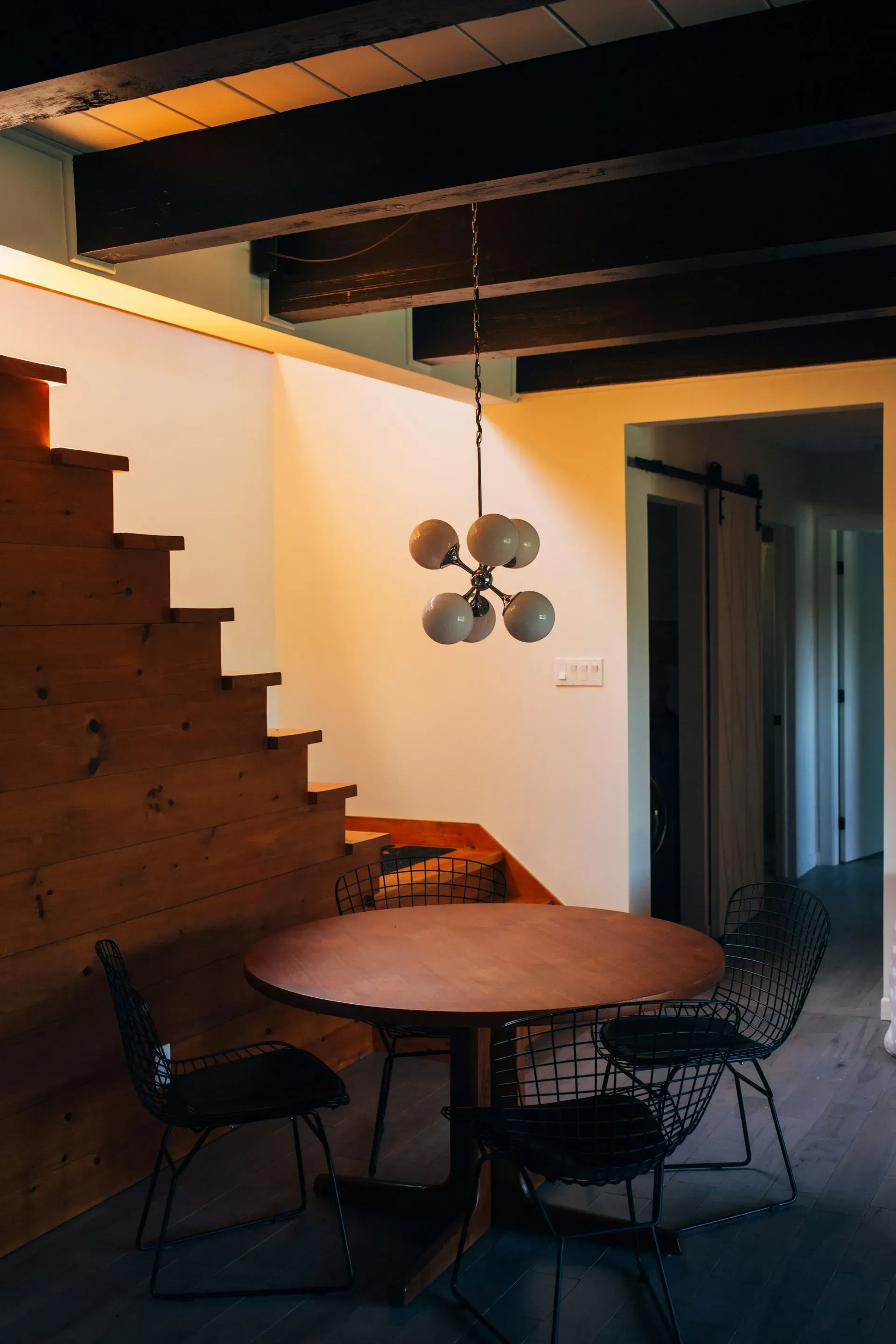 There is a table and chairs in the room with stairs.