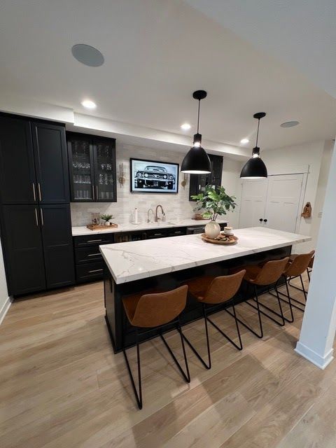 A kitchen with a large island and chairs and a tv on the wall. A kitchen with a large island and chairs and a tv on the wall.