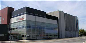 A large building with a lot of windows is sitting on the side of the road.