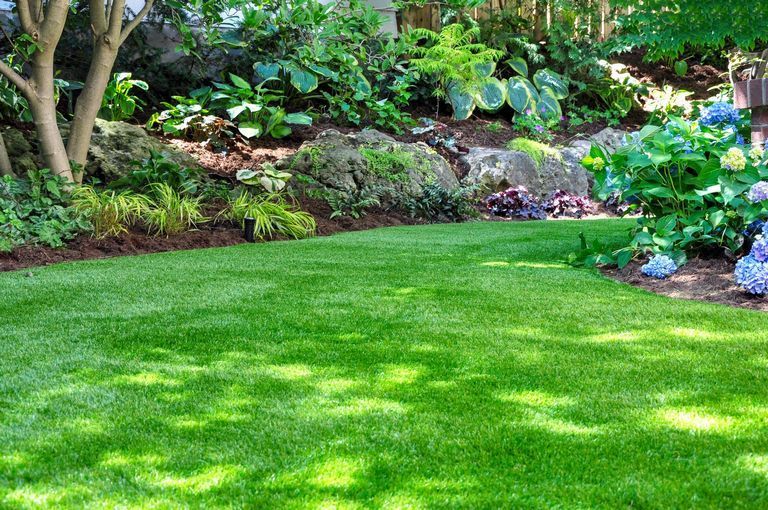 Beautiful backyard woodland garden features a freshly mowed lawn.