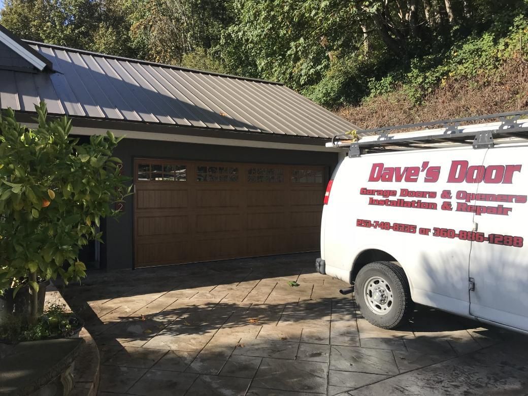 Garage with brown door, Dave's Door service van parked in front.