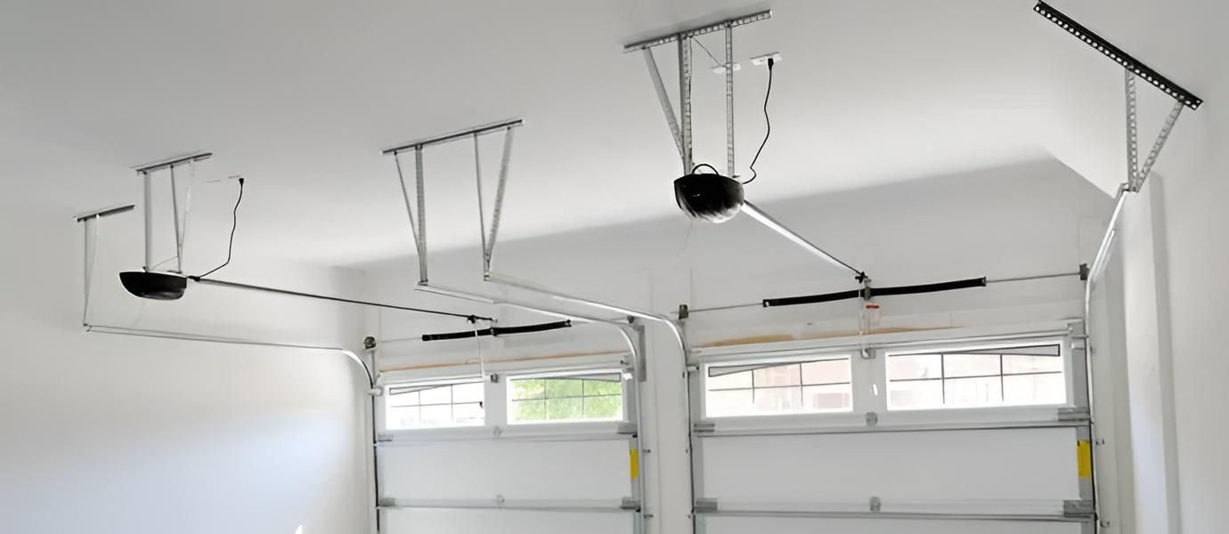 Two garage doors with automatic openers mounted on the ceiling.