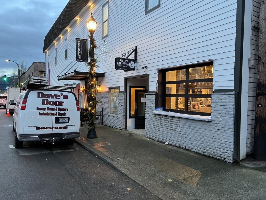 Exterior of a white building with black accents, decorated with string lights.