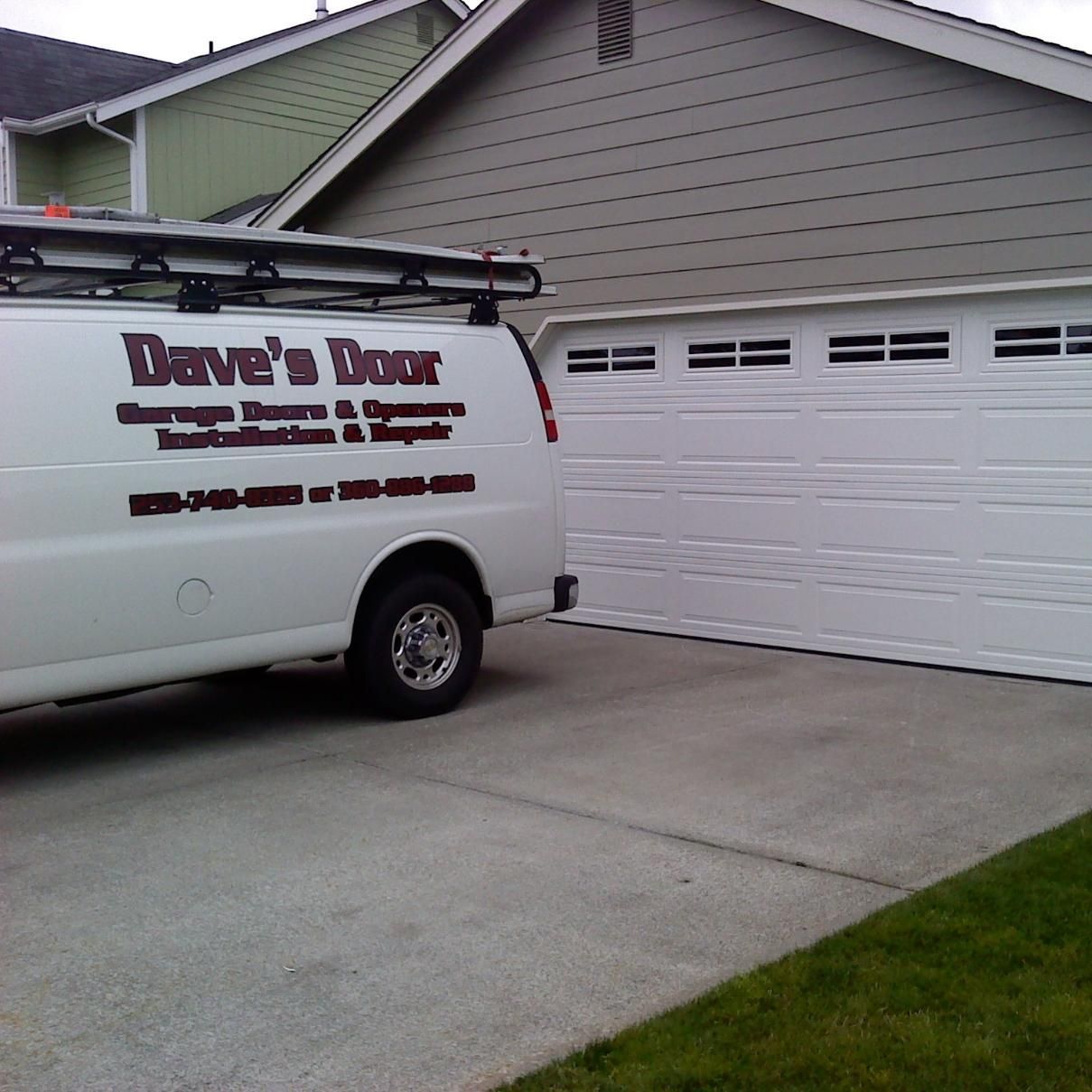 White van parked near a white garage door.