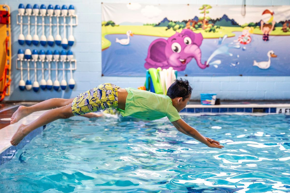 A young boy is diving into a swimming pool.