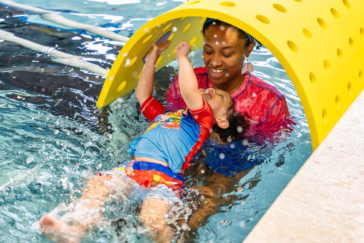Two young girls are playing with floats in a swimming pool.