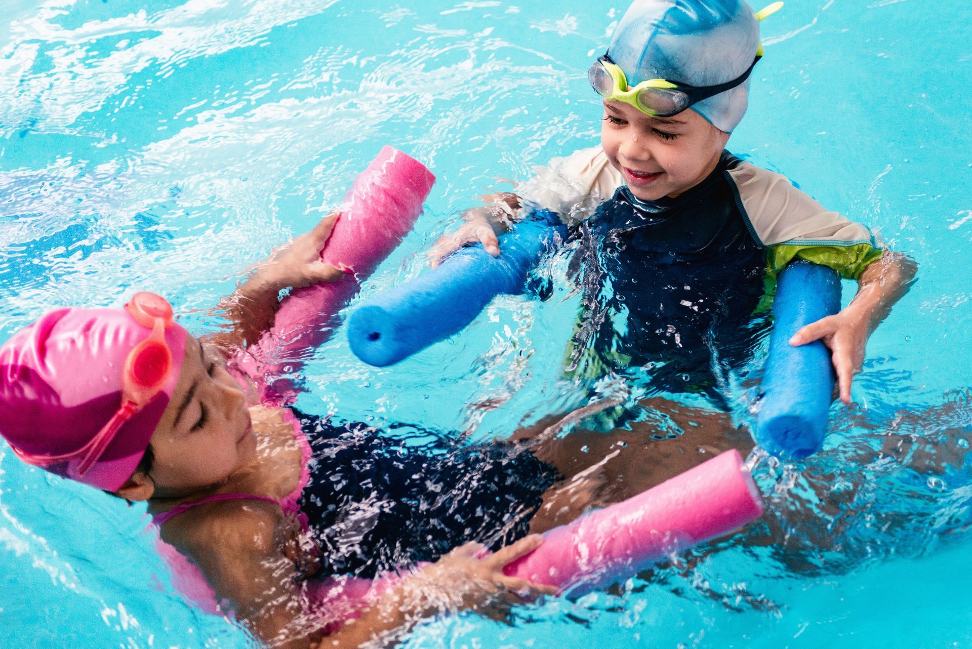 Two young girls are playing with floats in a swimming pool.
