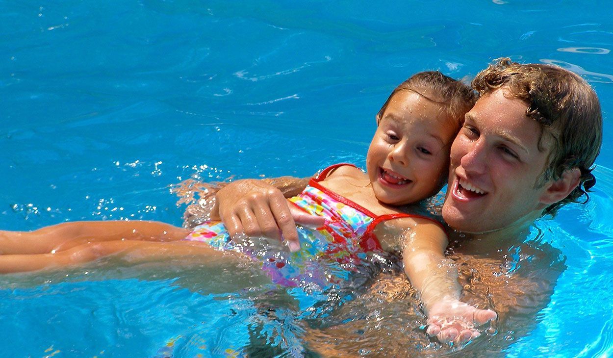 A man and a woman are posing for a picture in a swimming pool.