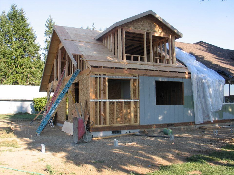 House under construction with exposed wooden framing and a blue siding section.