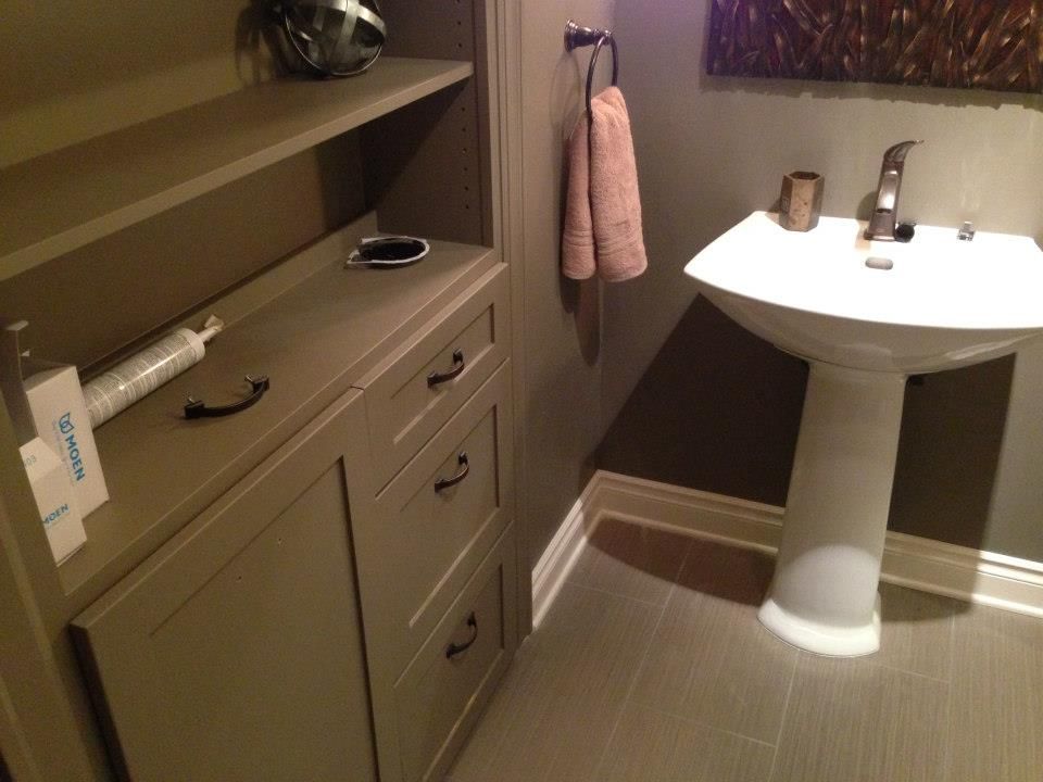 Small bathroom with pedestal sink and storage cabinet in shades of gray.
