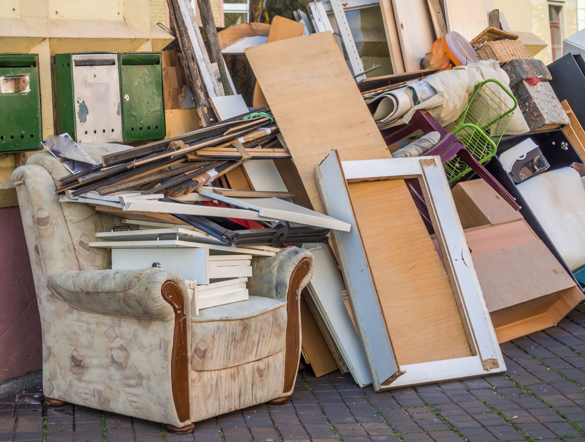 A pile of junk is sitting on a brick sidewalk in front of a building.