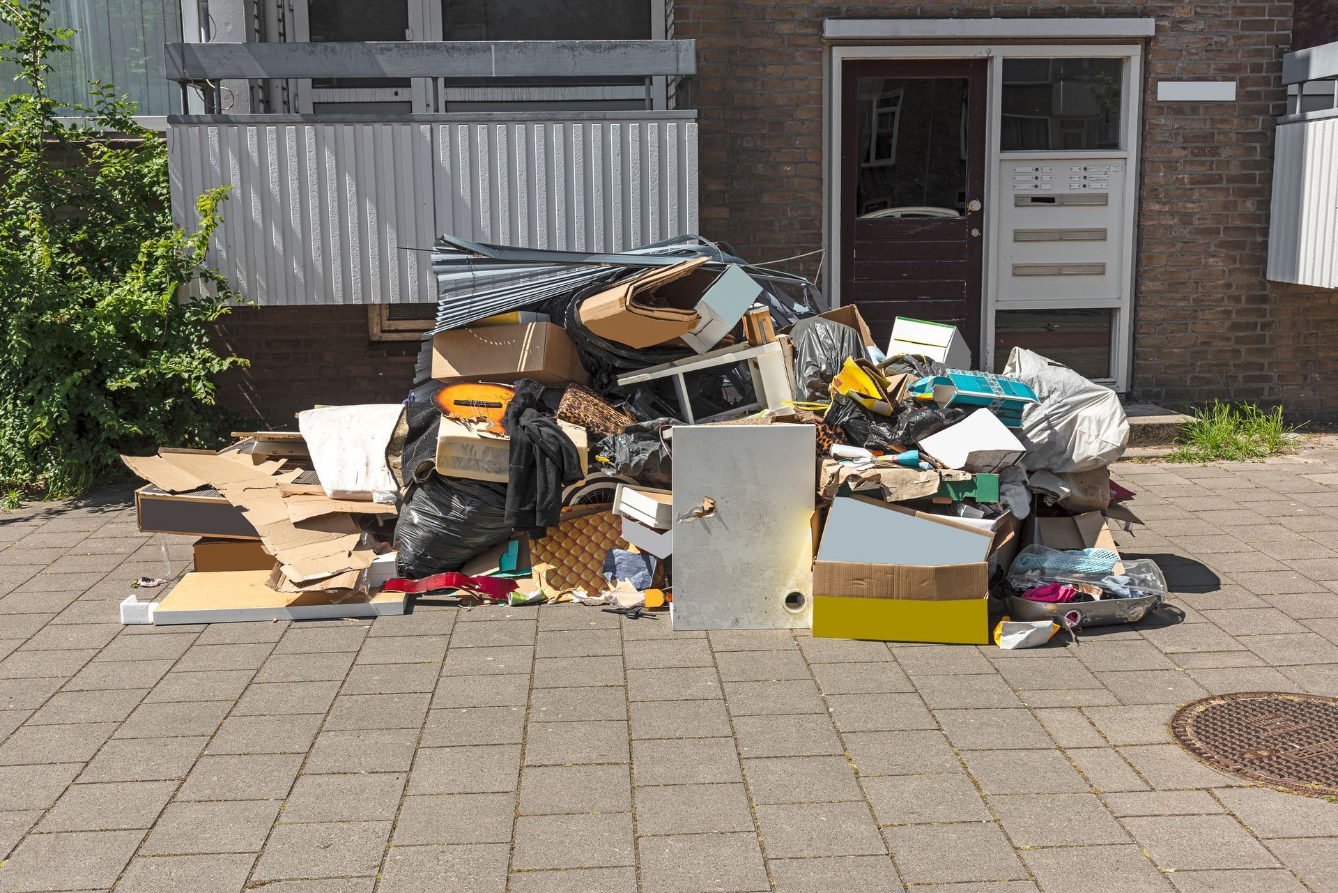 A pile of garbage is on the sidewalk in front of a building