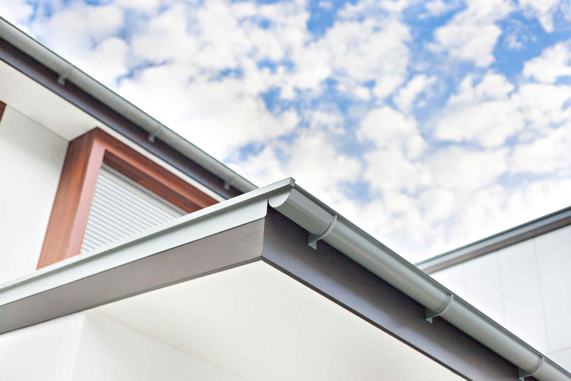 The roof of a house with a gutter and a window.