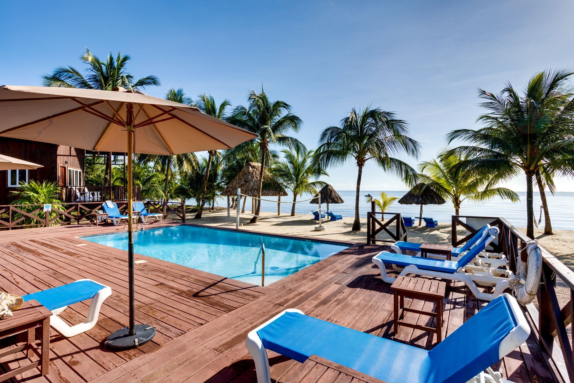 A swimming pool surrounded by chairs and umbrellas on a wooden deck