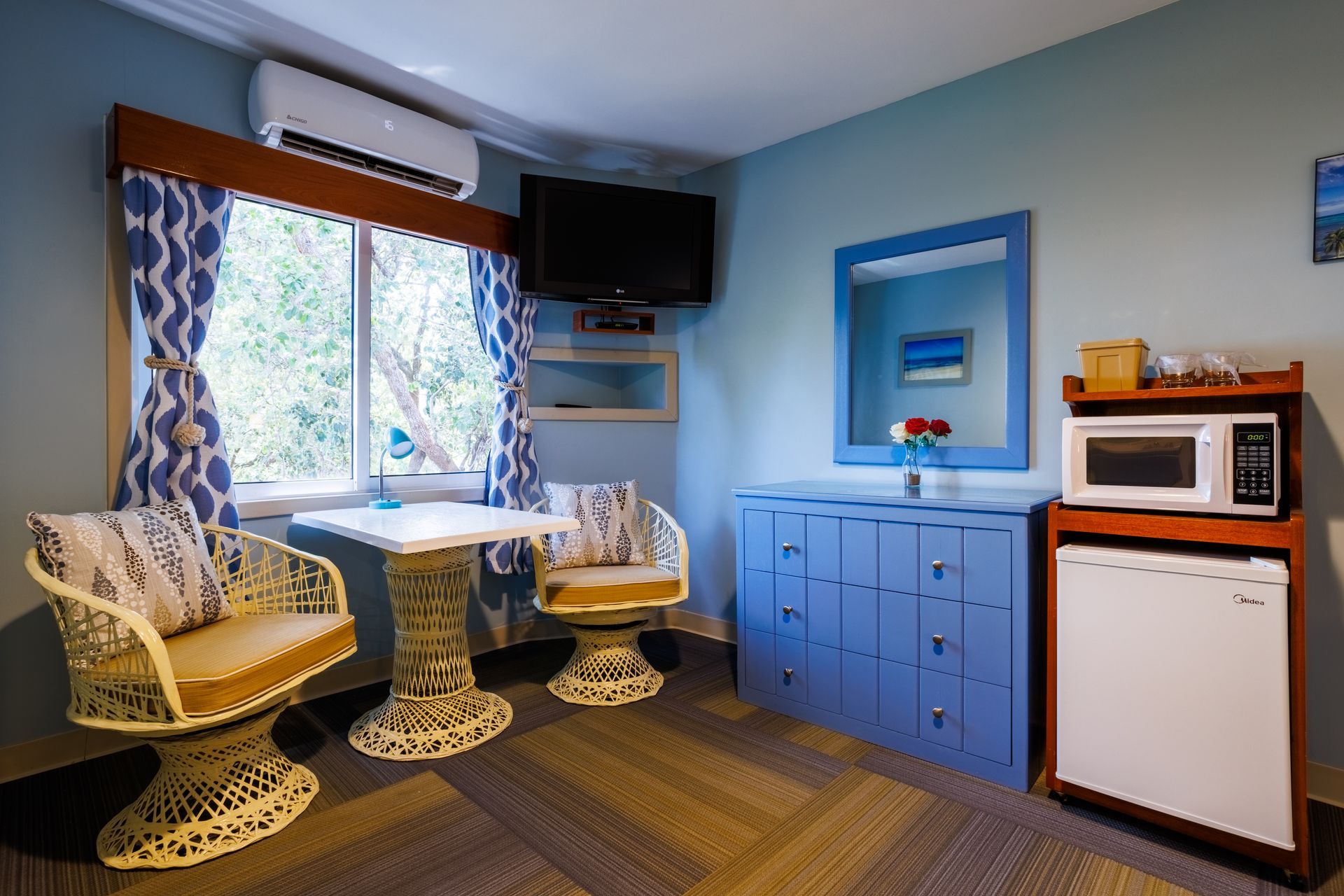 A living room with a table , chairs , a microwave and a television.