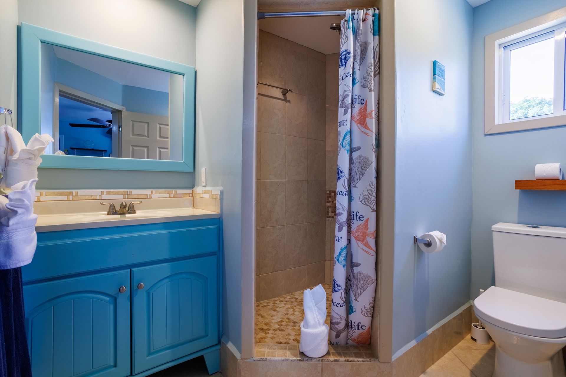 A bathroom with a toilet , sink , mirror and shower.