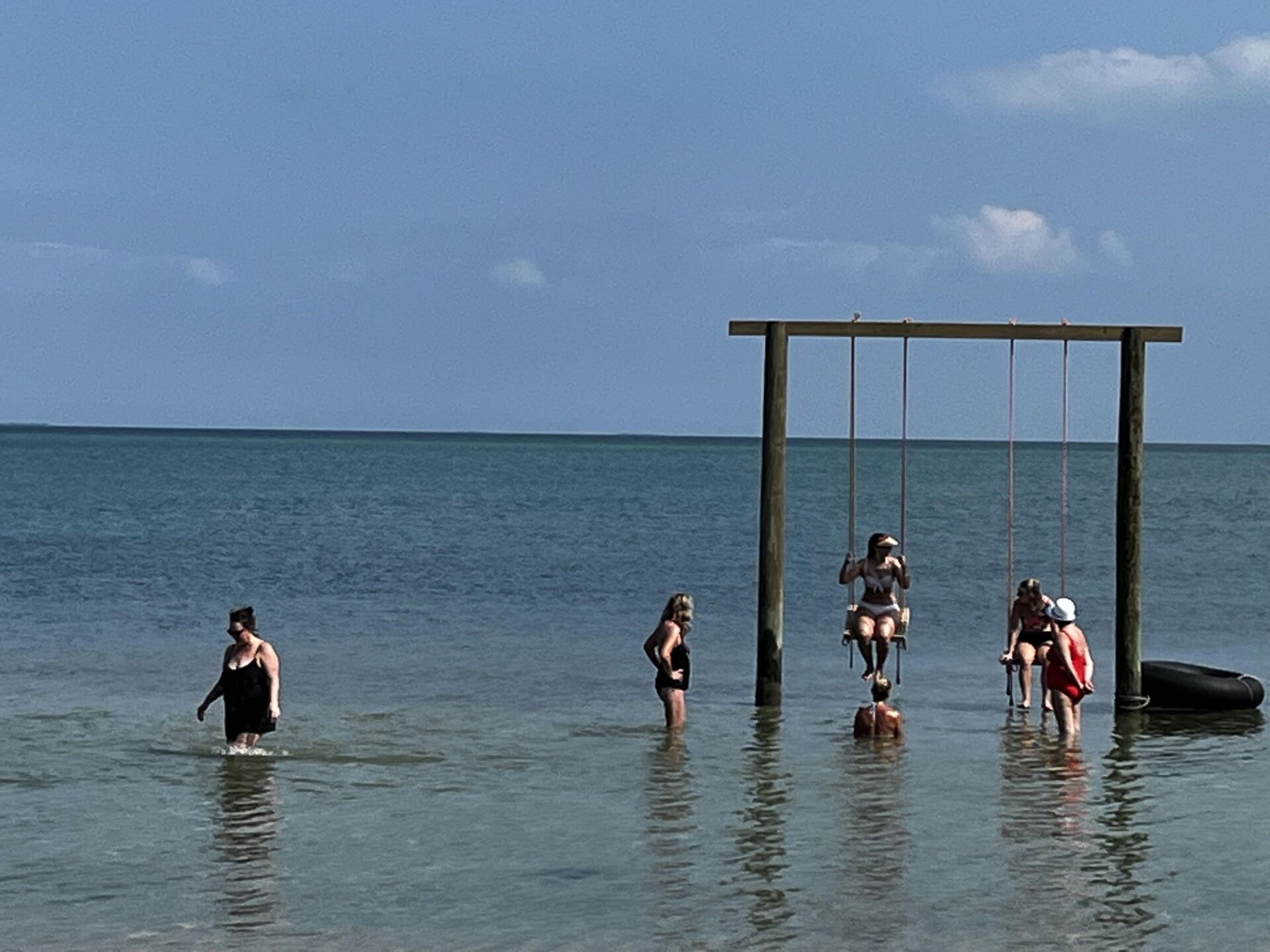 A group of people are playing in the water near a swing set