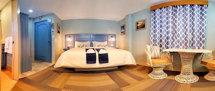 A hotel room with a king size bed , table and chairs.