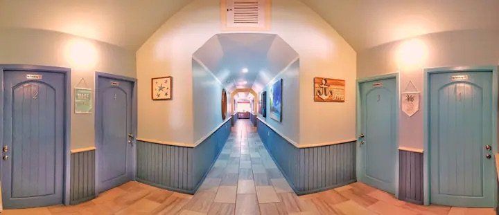 A long hallway with blue doors and a vaulted ceiling