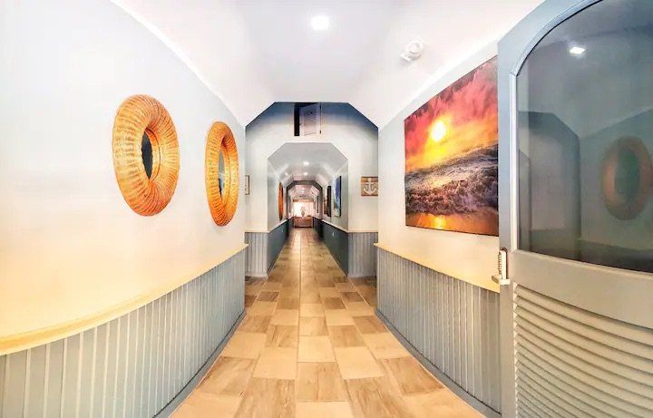 A long hallway with paintings on the walls and a door.