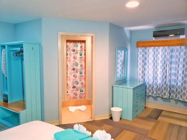 A bedroom with a bed , dresser , mirror and door leading to a bathroom.