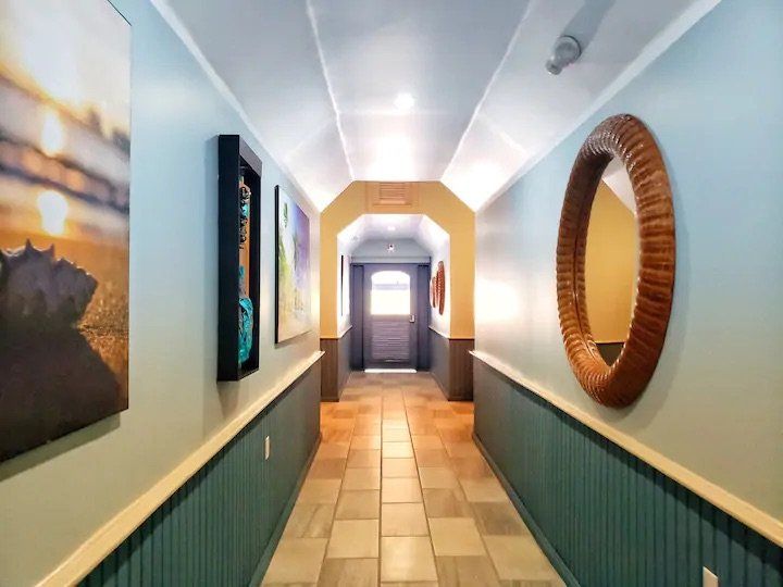 A long hallway with a mirror and paintings on the wall