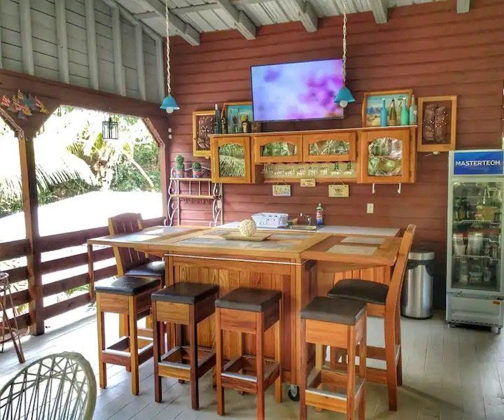 A large wooden bar with stools and a television above it