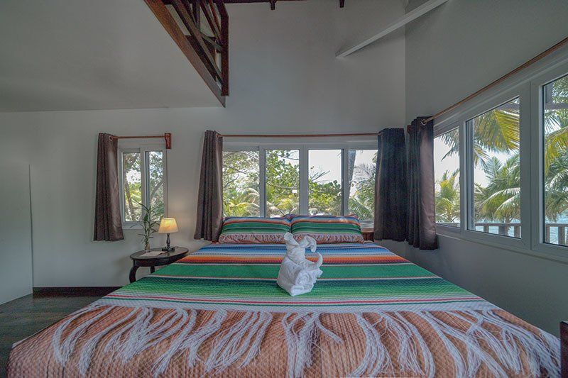 A bedroom with a king size bed and lots of windows.