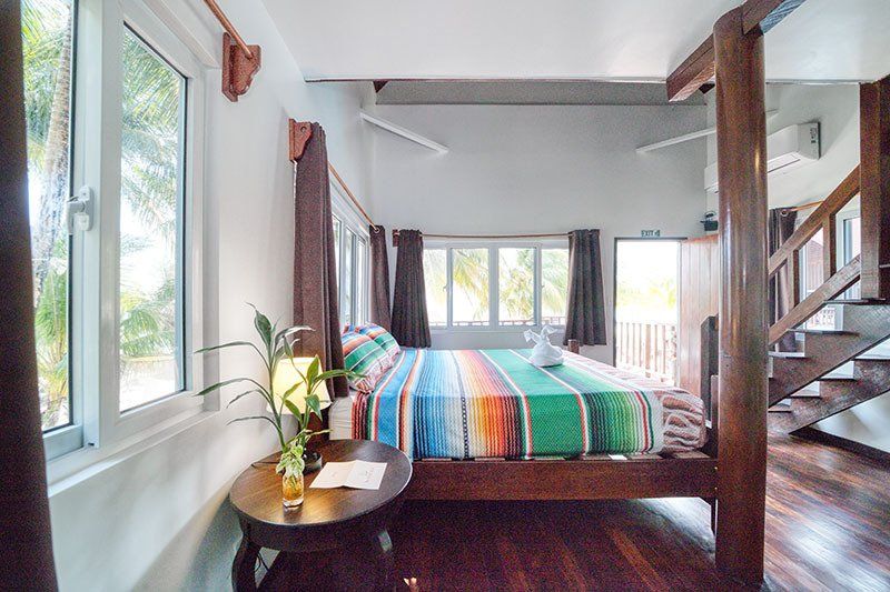 A bedroom with a king size bed , stairs , and a table.