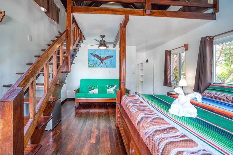 A bedroom with a bed , couch , and stairs leading to the second floor.