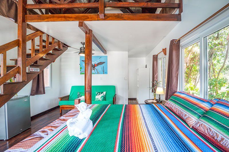 A hotel room with a bed , couch , and stairs.
