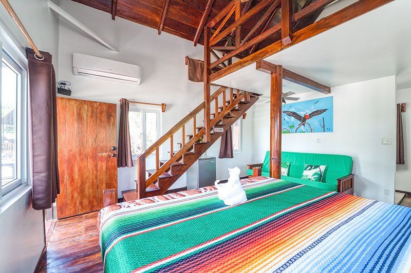 A hotel room with a king size bed and stairs leading up to the second floor.