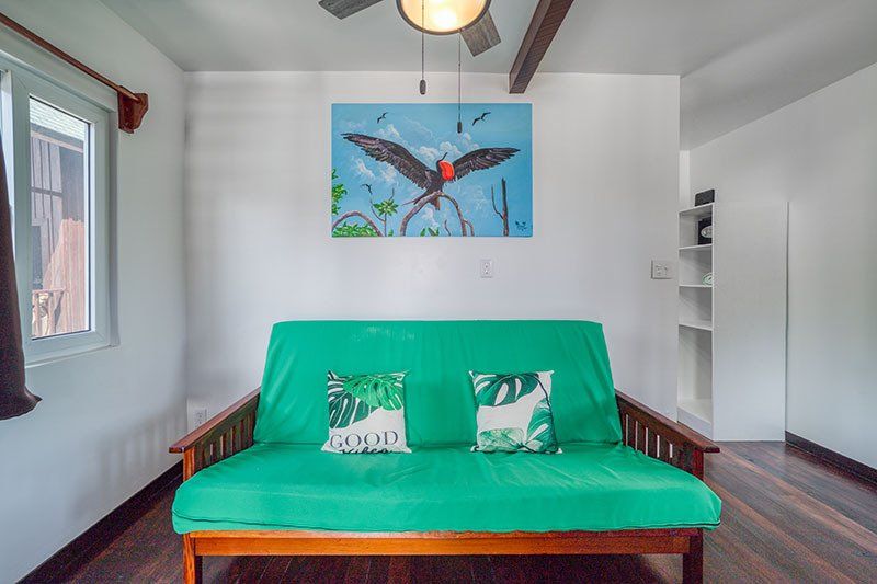 A living room with a green futon and a painting on the wall.