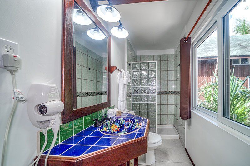 A bathroom with a toilet , sink , mirror and window.