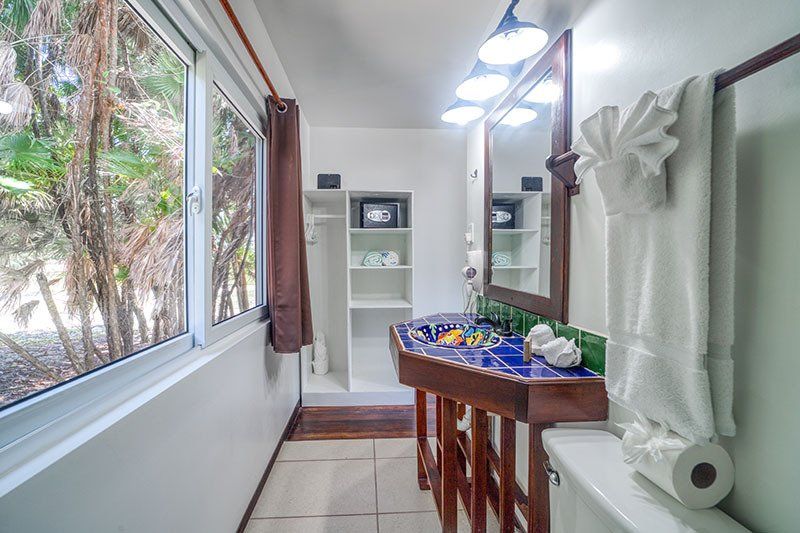 A bathroom with a sink , toilet , mirror and window.