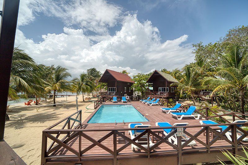 A large swimming pool is surrounded by chairs and a wooden deck.