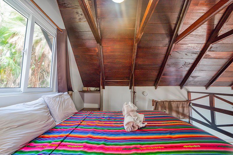 A bed with a colorful blanket on it in a room with a wooden ceiling.