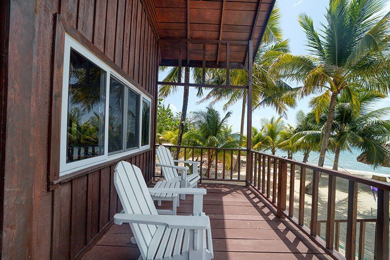 A wooden deck with chairs and a view of the ocean.