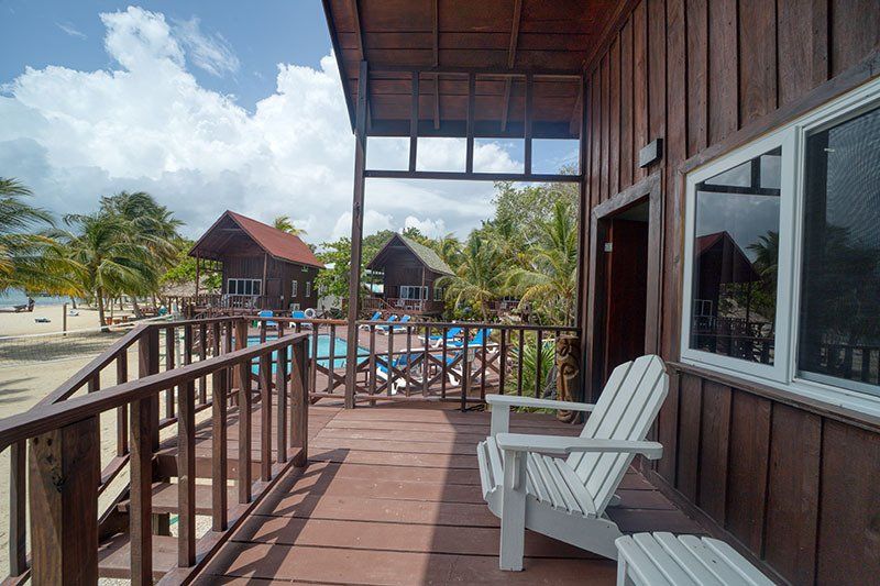There are two chairs on the deck of a wooden house.
