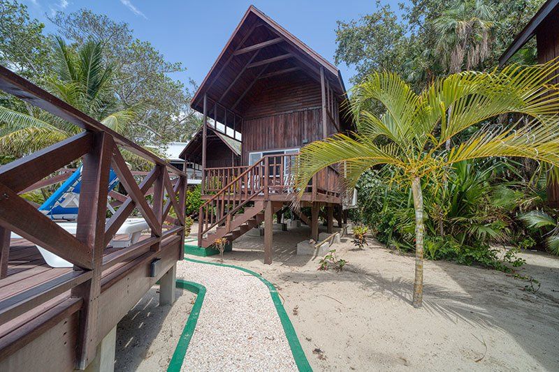 A wooden house on stilts with a green hose in front of it.