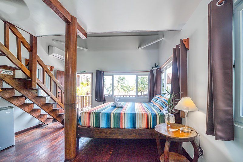 A bedroom with a bed , stairs , a table and a lamp.