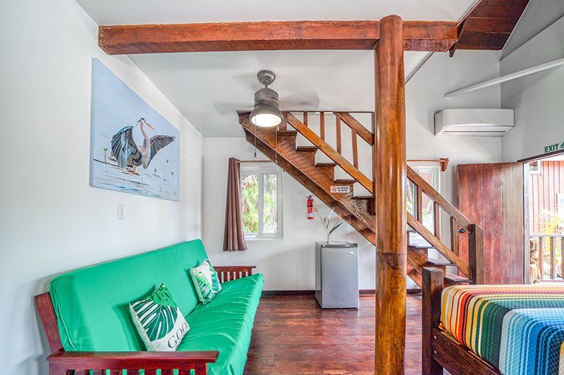 A living room with a green couch and stairs leading up to the second floor.