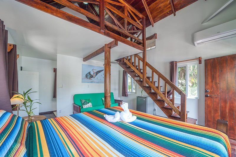 A bedroom with a bed , stairs and a green couch.