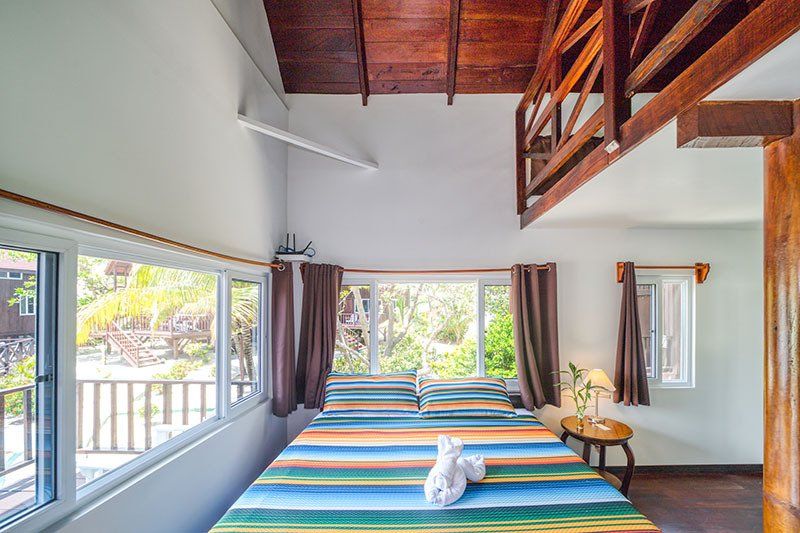 A bedroom with two beds , a table , and a balcony.