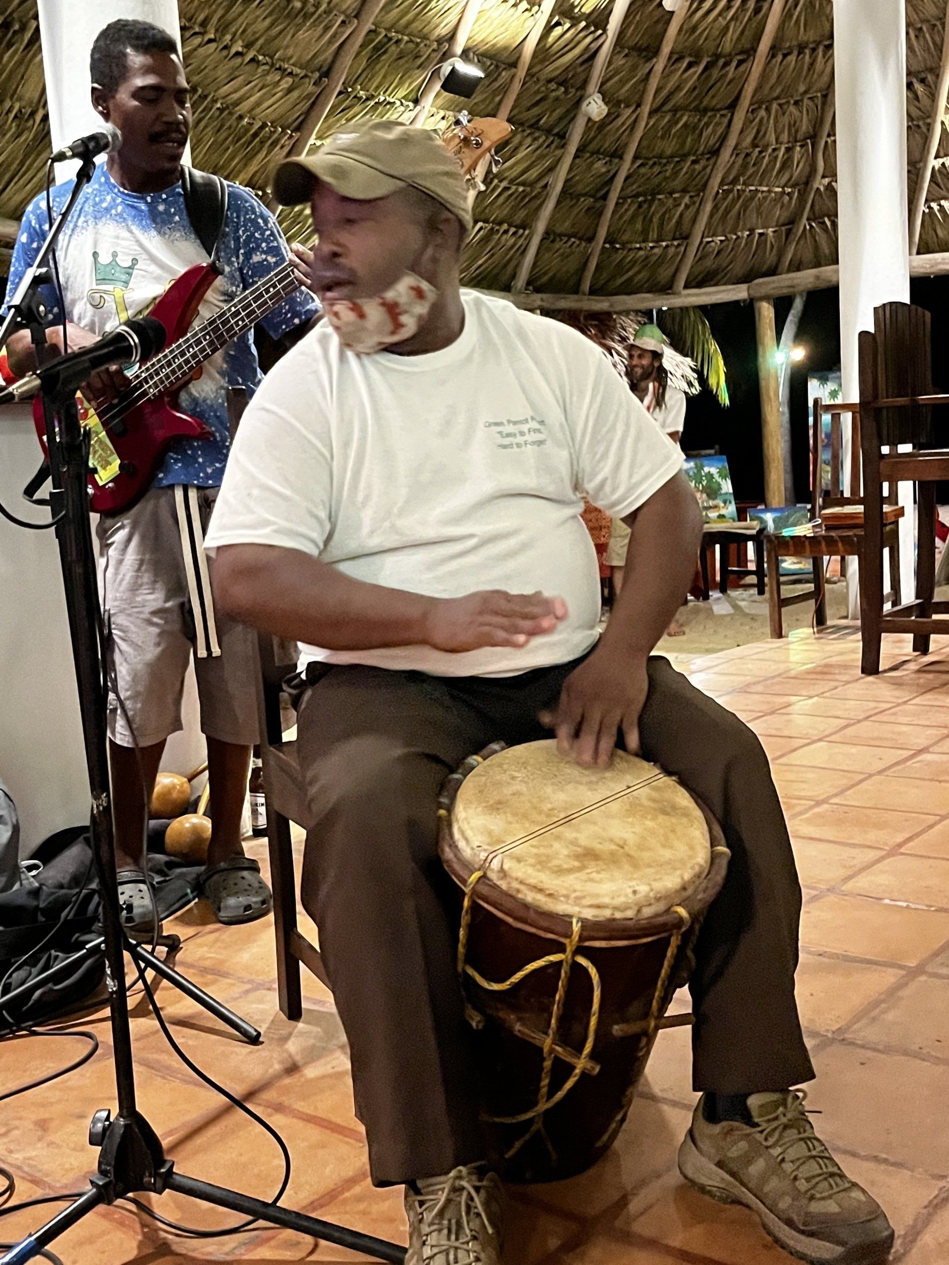 A man is playing a drum while another man plays a guitar